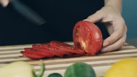 Close up shot hands of women using kitchen knife slide cut fresh tomato on wo Stockbeeldmateriaal 112774821