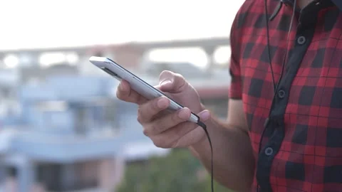 Close-up shot of hands of young man typing message on mobile phone outdoors. Stock Footage 148915796