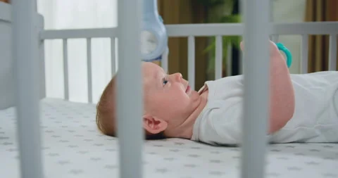 Close up shot of happy cute 2-3 month child lying in white crib, infant moving Stock Footage 219342039