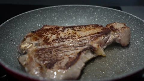 Close up shot of a healthy T-bone steak cooking in the pan. beef meat Stock Footage 215919856