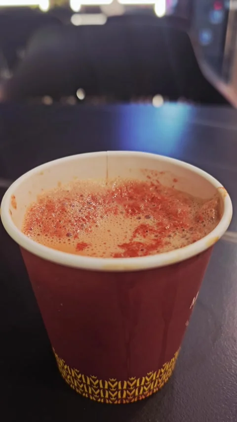 ​A close-up shot of hot, frothy fresh milk tea served in a maroon disposable Stock Footage 335501975