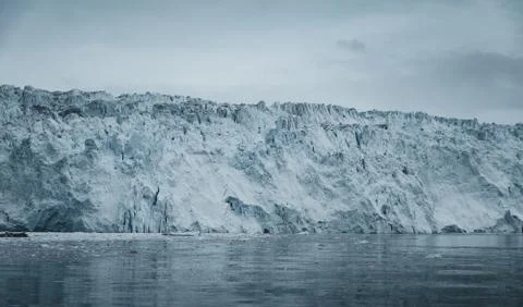 Close Up shot of huge Glacier wall. Large chunks of ice breaking off. Moody and Stock Photos