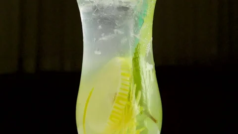 Close-up shot of ice being thrown into a glass of lemonade. Slow motion. HD 動画素材 107558873