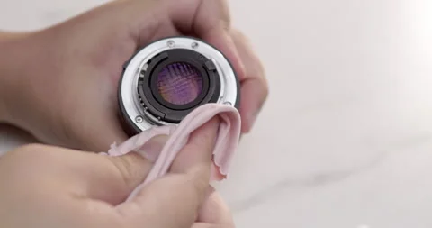Close-up shot of an individual cleaning a camera lens using a piece of Stock Footage 277196469