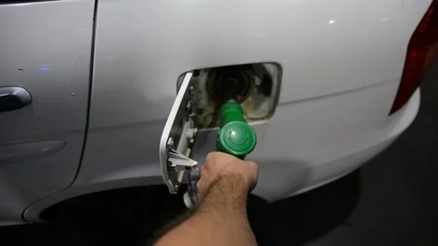 Close up shot of insertion of the nozzle and pumping gasoline into a white vehic Vídeos de archivo 94041739