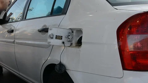 Close up shot of insertion of the nozzle and pumping gasoline into a white vehic Vídeos de archivo 94843760