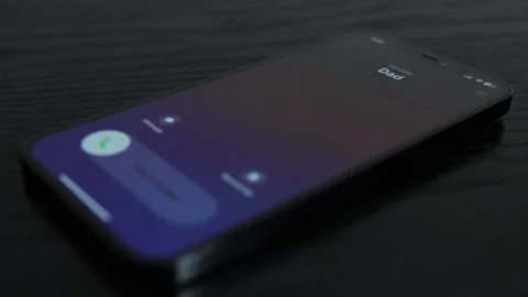 Close-up shot of an iPhone receiving a call from Dad on black wooden table Stock Footage 273055267