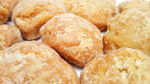 Close up shot of Jaggery or Gur pieces on white background moving. sugar cane Stock Footage 282583727