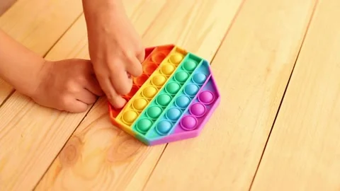 Close up shot of kid hands playing with colorful pop It fidget toy. Anti-stress Stock Footage 164473461