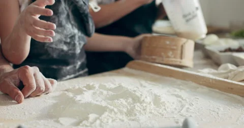 Close up shot kid's hands helping young mother and father sieving flour through Stock Footage 218629342