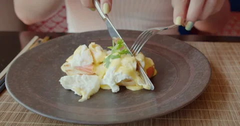 Close up shot Knife and fork in woman hands with bright manicure cut pouched egg Stock Footage 164789458