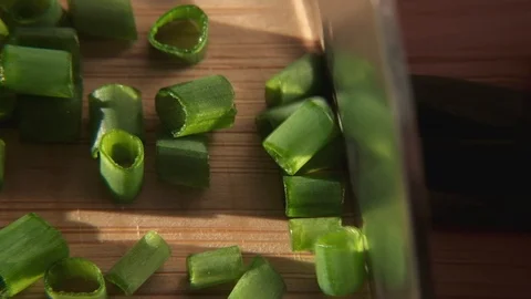 Close up shot of knife chopping spring onion on wooden cutting board. 4K Stock Footage 118547242