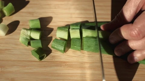 Close up shot of knife chopping spring onion on wooden cutting board. 4K Stock Footage 118547547