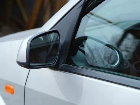 A close-up shot of the left side mirror of a silver car. Stock Photos