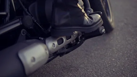 Close up shot of a leg in black boots of anonymous biker girl shifting gears Stock Footage