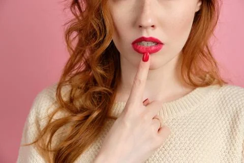A close shot of the lips of a red-haired girl with red lipstick and a finger Stock Photos