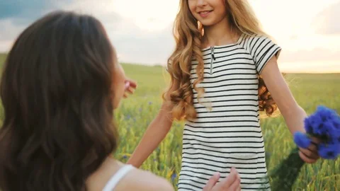 Close up shot of little daughter running to mother with beatiful bouquet of Stock Footage