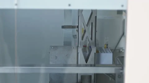 Close shot of a machine taking a test tube out of a tray in an automated lab Stock Footage 232687397