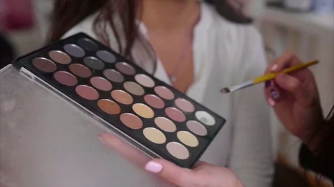 Close up shot of make up artist taking eye shadows from make-up palette by brush Stock Footage 70146852