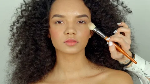 Close up shot of the makeup artist's hands, who puts a blush on the woman's face Stock Footage 88860341