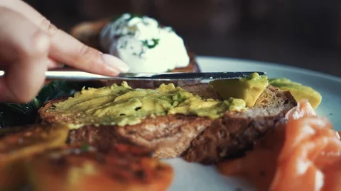 Close-up shot of making a healthy snack with dark rye bread and avocado spread Stock Footage 127598532