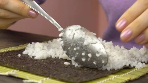 Close-up shot of making sushi at home. Female hands spread sushi rice on nori Stock-Footage 149851188
