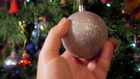 Close-up shot of male hands attaching shiny Christmas ball to Christmas tree Stock Footage 225511871