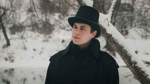 Close-up shot: A man in black cloak and hat stands on the banks of the river and 動画素材 102188910