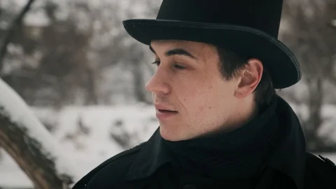 Close-up shot: A man in black cloak and hat stands on the banks of the river and 스톡 동영상 102189112