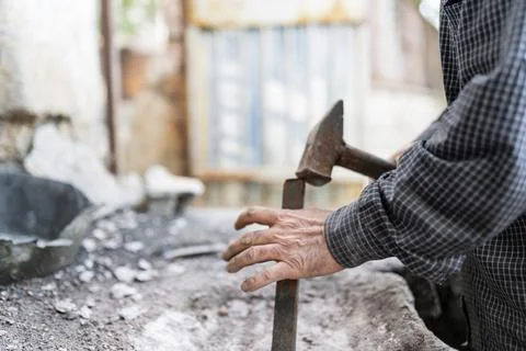 Close-up shot of a man breaking down a wall using a hammer and chisel. Stock Photos