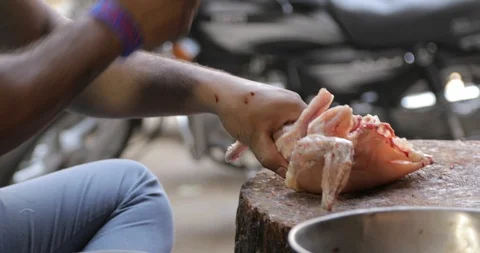 A close-up shot of a man chopping raw chicken into pieces Video stock 86375081