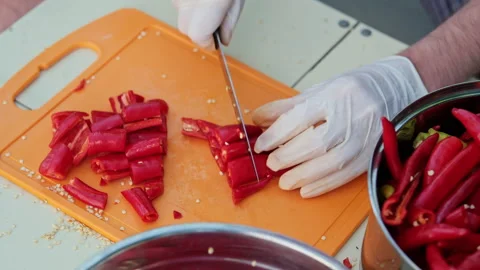Close up shot of a man cutting red hot peppers, wearing white latex gloves. Stock Footage 286377261