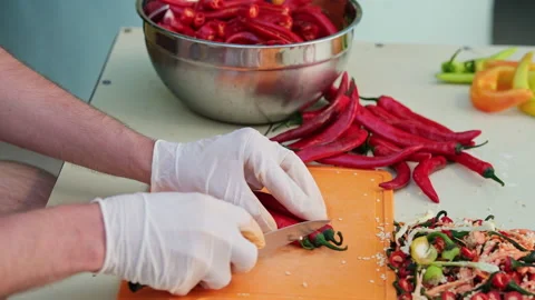 Close up shot of a man cutting red hot peppers, wearing white latex gloves. S Video stock 286416251