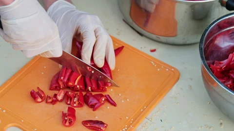Close up shot of a man cutting red hot peppers, wearing white latex gloves. Stock Footage 286416519
