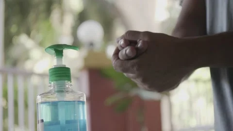 Close up shot of a man disinfecting hands using alcohol-based hand sanitiser 130257935