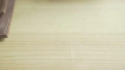 Close up shot of man hand putting silver ball pen into pen holder on light brown Stock Footage 137539196
