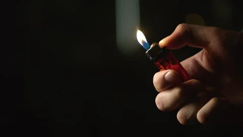 Close up shot of man hand using fire of lighter against black background Stock Footage 168950107