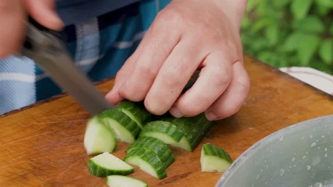 Close shot of man hands cutting cucumber with a knife on wooden board Stock Footage 111649276