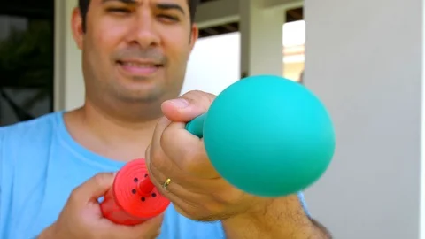 Close up shot of man hands inflating a green balloon with a pump Stock Footage 123656233