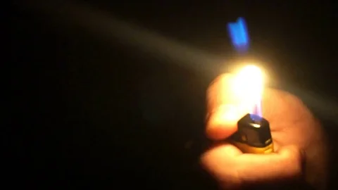 A close-up shot of a man igniting a lighter in the dark Stock Footage 77157814