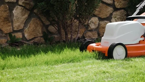 Close up shot of a man mows the grass in the backyard with an electric lawn Stock Footage 162877588