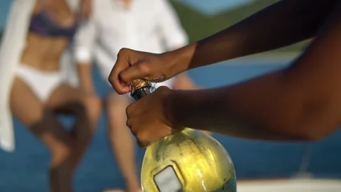 Close-up shot of man opens bottle of champagne, young company has rest on yacht Stock Footage 119633079