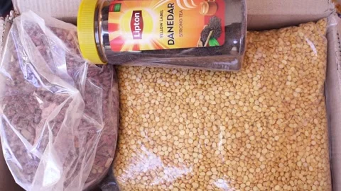 Close-up shot of a man putting dates package in a carton filled with chickpeas,  Vidéo 165841794