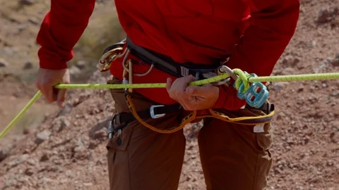 Close shot of a man rappelling down a rope in the desert. Stock Footage 124937008