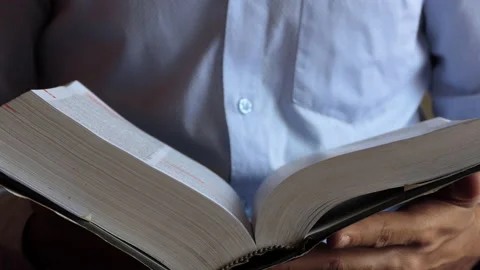 Close shot of a man reading the page of a thick book Stock Footage 146964168