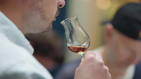 Close-up shot of a man smelling amber liquor in a tasting glass during a Stock Footage 333806004