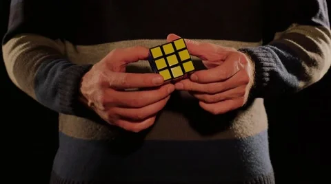 Close up shot of a man solving the Rubik´s cube, isolated on a black background Stock Footage 60672423
