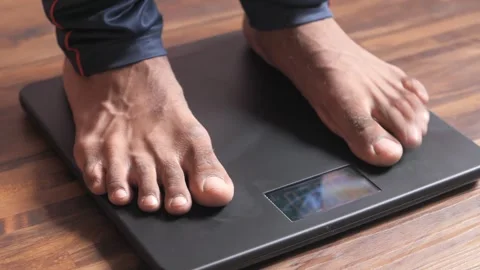 A close up shot of a man standing on a digital weighing scale to measure hi.. Vídeo Stock 333153420