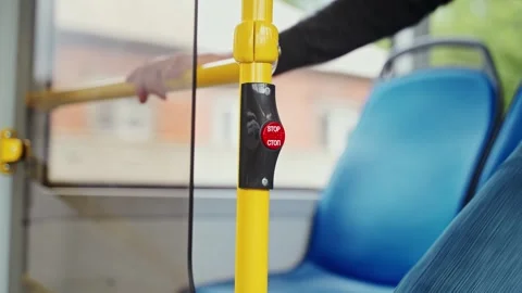 Close up shot man stands up to push red stop button on handrail in moving bus Stock Footage 256994709