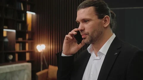 Close-up shot of man in suit talking on the phone in dark office Video stock 166968381